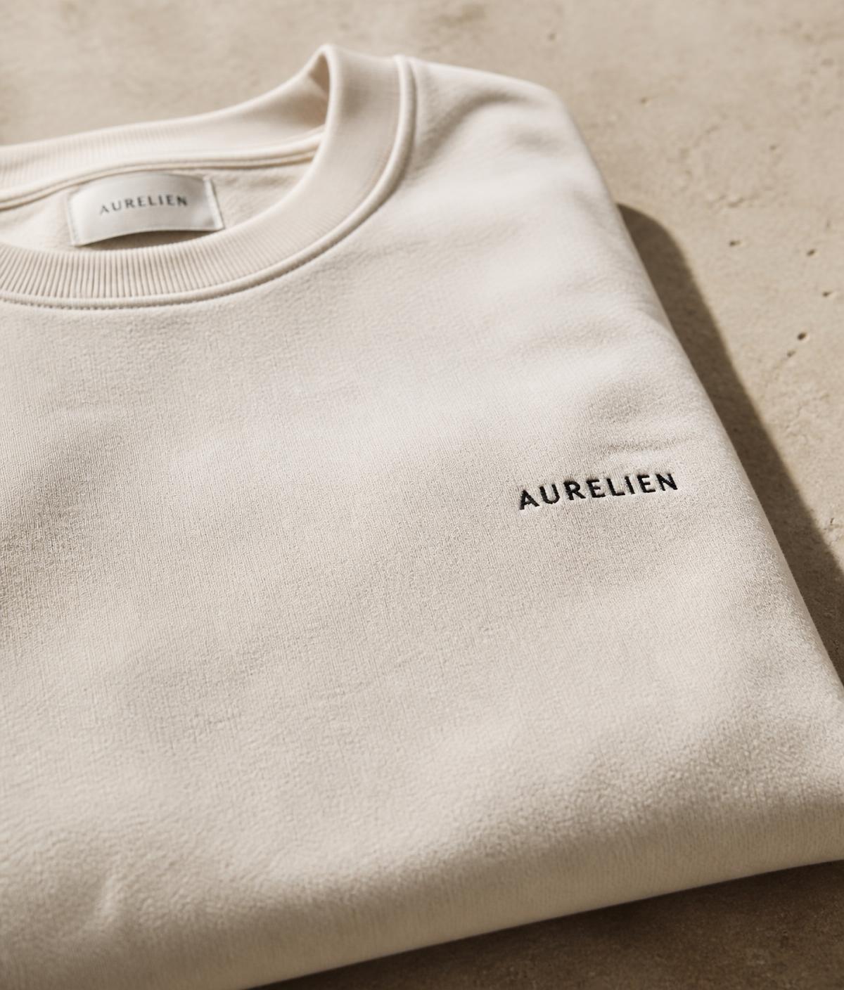 Folded premium cream sweatshirt with a small embroidered wordmark
